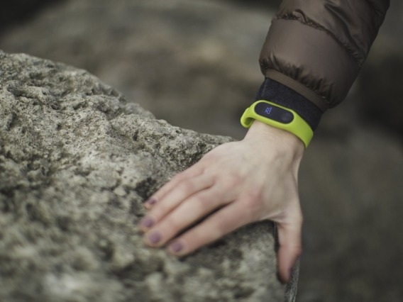 Person's arm with wearable technology device (Fitbit) holding onto a rock for support.
