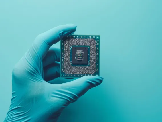Gloved hand with computer central processing unit on light blue background.
