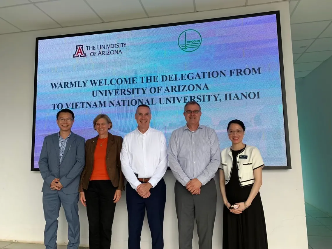 VNU MOU signing in Vietnam, U of A delegation with hosts in front of welcome sign.