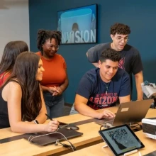 A group of students working around a laptop